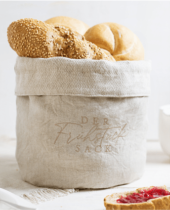 Das Sackgeschäft - Frühstücksack aus Leinen mit frischem Gebäck und Marmeladebrot im Vordergrund
